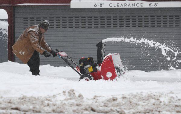 A maintenance man uses a snowblower to clear a sidewalk outside a condominium complex along Grant Street as a storm packing snow and high winds sweeps in over the region on Nov. 26, 2019, in Denver. (David Zalubowski/AP Photo)