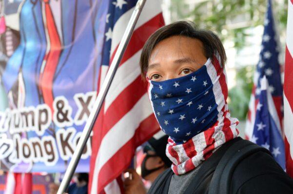 A protester stands in front of U.S. flags at a rally at Charter Garden in Hong Kong on Dec. 1, 2019. (Sun Pi-lung/The Epoch Times)