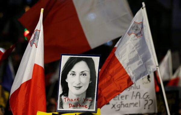 A picture of Daphne Caruana Galizia is seen next to flags of Malta during a demonstration demanding justice over the murder of the journalist, outside the Court of Justice in Valletta, Malta, on Dec. 1, 2019. (Darrin Zammit Lupi/Reuters)