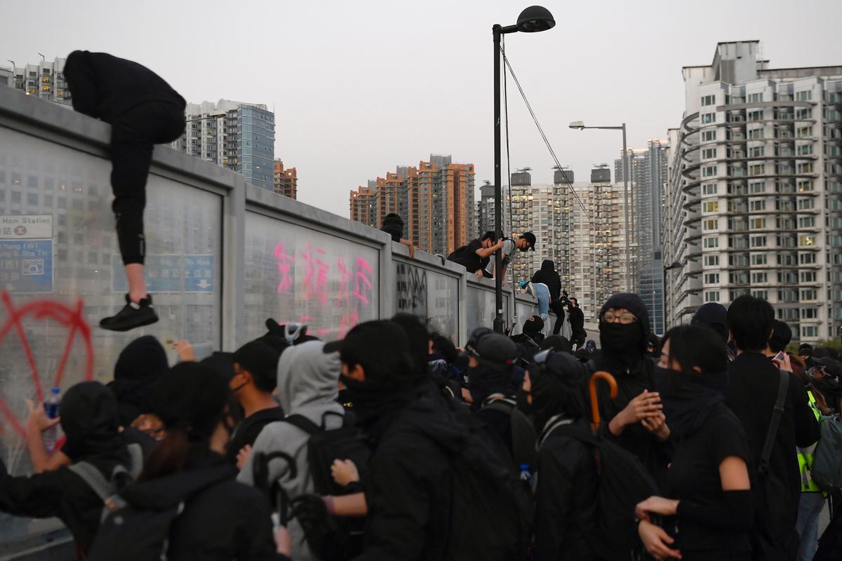 Protesters climb a wall during the "Lest We Forget" rally in Kowloon in Hong Kong on Dec. 1, 2019. (Laurel Chor/Reuters)