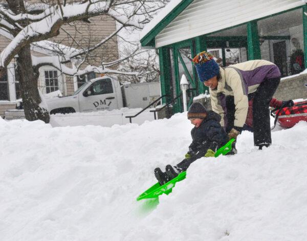 Edisa Weeks gives her 5-year-old nephew, Niko Brown, a push down a hill at the Brattleboro Little League Field, in Brattleboro, Vt., on Dec. 2, 2019. (Kristopher Radder/The Brattleboro Reformer via AP)