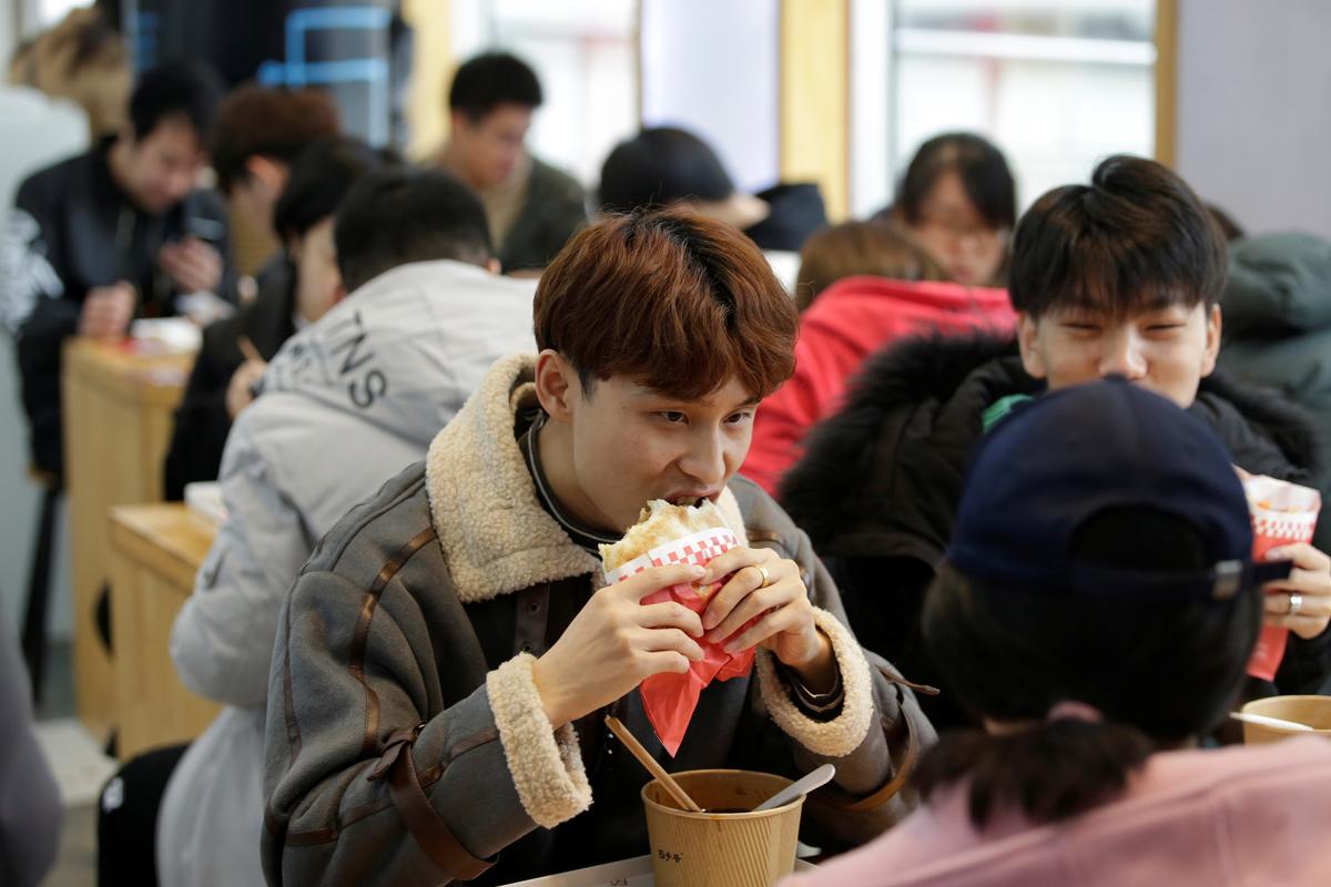 A customer eats a baked bun with chicken at a pork bun chain restaurant Xishaoye in Beijing, China on Nov. 22, 2019. (Jason Lee/Reuters)