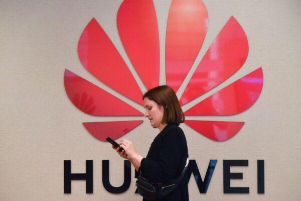 A woman walks by the Huawei logo at an event in Brussels, Belgium, on May 21, 2019. (Emmanuel Dunand/AFP/Getty Images)
