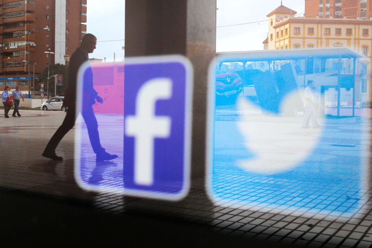 Facebook and Twitter logos are seen on a shop window in Malaga, Spain, on June 4, 2018. (Jon Nazca/Reuters)