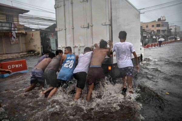 Residents help push a stalled van off a flooded highway during the onslaught of Typhoon Kammuri in Lipa town, Batangas Province, Philippines, on Dec. 3, 2019. (Ezra Acayan/Getty Images)