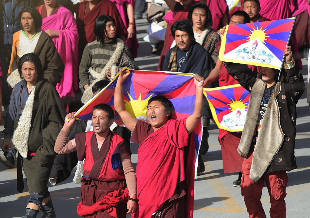 Protesters led by Tibetan Buddhist monks shout slogans and carry the Tibetan national flag after being blocked by riot police at a protest near the historic Labrang Monastery, which is second only to the Potala Palace in Lhasa in size, in the town of Xiahe, Gansu Province, on March 14, 2008. The protests coincided with a week of protests against Chinese rule inside Tibet, which began with demonstrations marking the anniversary of a failed 1959 uprising by Tibetans. (Mark Ralston/AFP via Getty Images)
