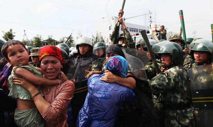 Chinese policemen push Uighur women who are protesting at a street in Urumqi, the capital of Xinjiang, on July 7, 2009. (Guang Niu/Getty Images)