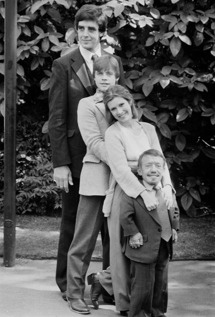 (L–R) Actors Peter Mayhew, Mark Hamill, Carrie Fisher, and Kenny Baker, co-stars in the first "Star Wars" trilogy, pictured in England on May 20, 1980. (©Getty Images | <a href="https://www.gettyimages.com/detail/news-photo/actor-peter-mayhew-mark-hamill-carrie-fisher-kenny-baker-co-news-photo/1097762268?adppopup=true">Chris Ball</a>)
