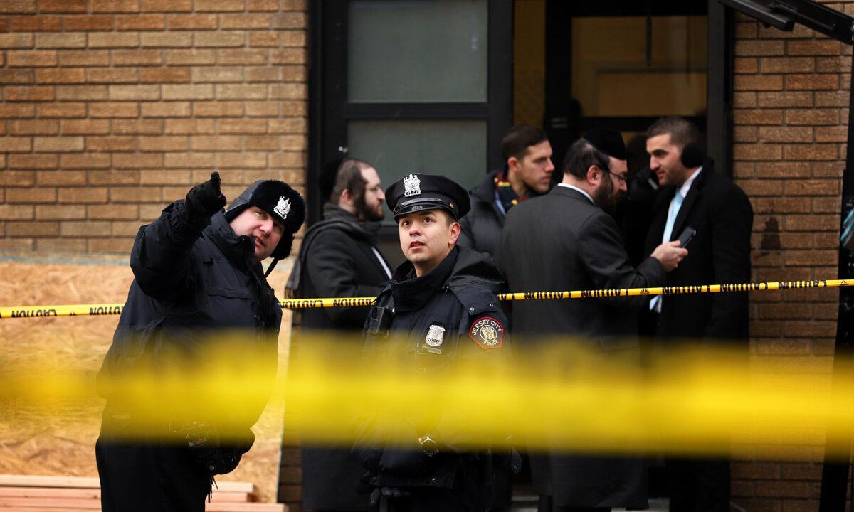 Police officers look at bullet holes in the windows of a school across the street from the JC Kosher Supermarket in Jersey City, N.J., on Dec. 11, 2019. Six people, including a Jersey City police officer and three civilians were killed in a deadly, hours-long gun battle between two armed suspects and police in a standoff and shootout in a Jewish market that appears to have been targeted, according to Jersey City Mayor Steven Fulop. Rick Loomis/Getty Images