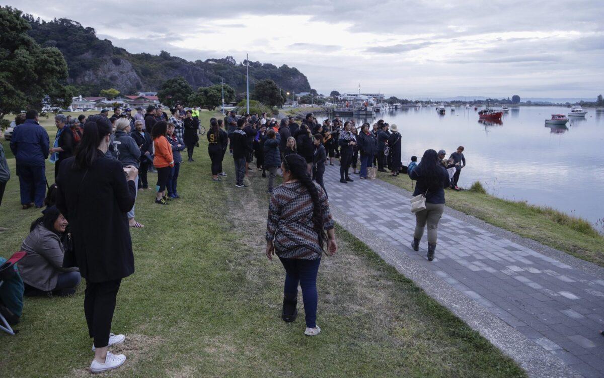 Locals sing during sunrise as they wait for the return of the victims after the White Island eruption to be returned to Whakatane, New Zealand, on Dec. 13, 2019. (AP Photo/Mark Baker)