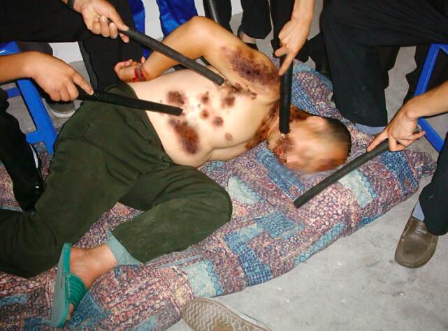 Torture reenactment of Falun Gong practitioner being shocked and beaten with electric batons. (<a href="https://en.minghui.org/">Minghui</a>)