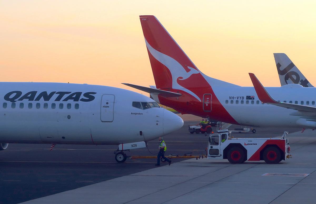 Workers are seen near Qantas Airways, Australia's national carrier, Boeing 737-800 aircraft on the tarmac at Adelaide Airport, Australia, on Aug. 22, 2018. (Reuters/David Gray)