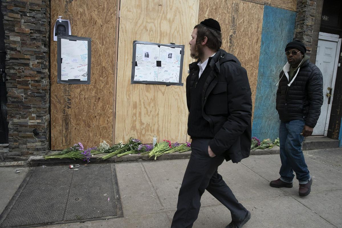 Men pass a boarded-up kosher grocery store in Jersey City, New Jersey on Dec. 13, 2019, where three people and two shooters were killed. (AP Photo/Mark Lennihan)