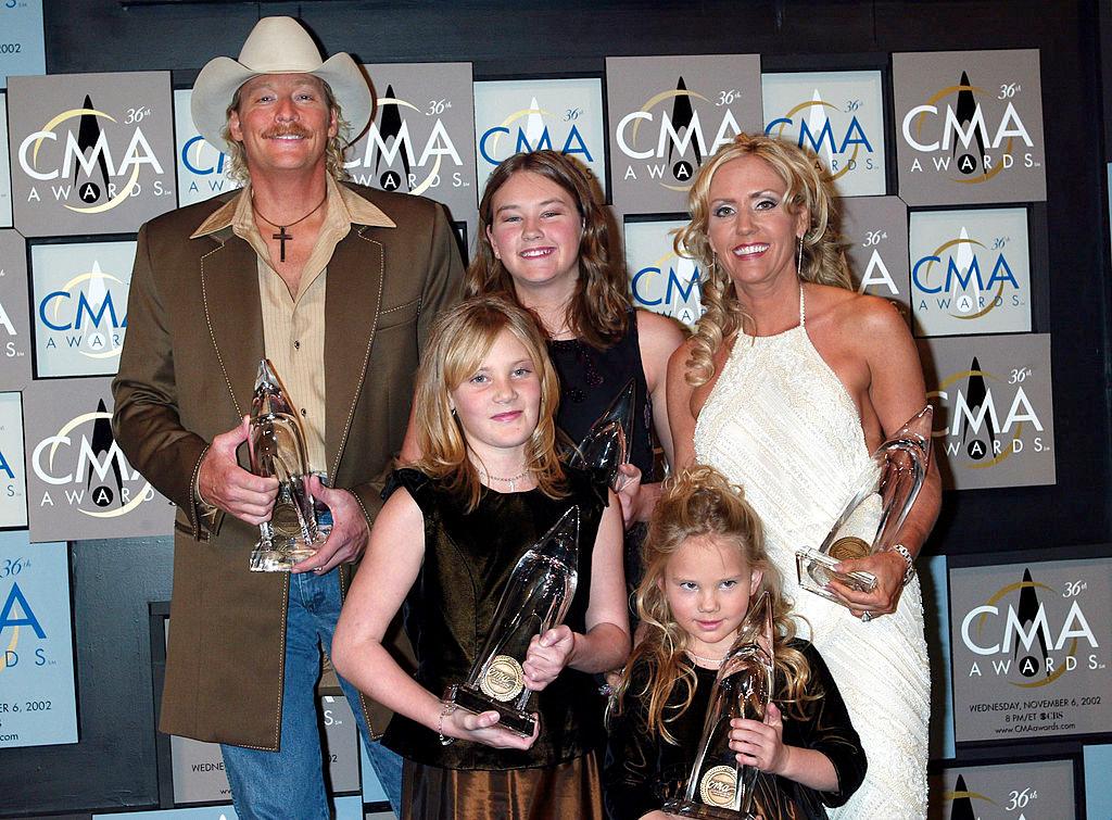 Jackson poses with his five awards at the CMA's at the Grand Ole Opry House in Nashville, Tennessee, accompanied by (L–R) Alexandra, Mattie, Dani, and Denise on Nov. 6, 2002. (©Getty Images | <a href="https://www.gettyimages.com/detail/news-photo/alan-jackson-poses-with-his-5-awards-with-a-little-help-news-photo/2293148?adppopup=true">Scott Gries</a>)