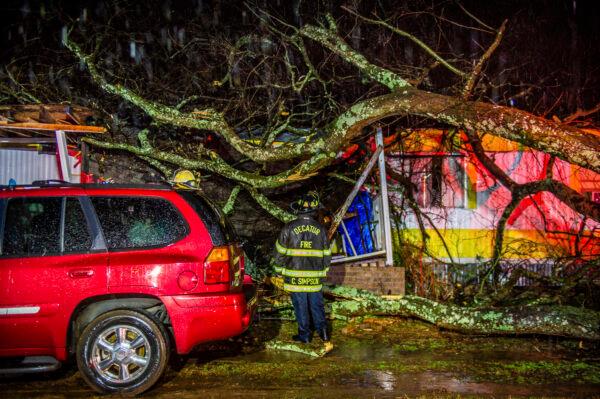 Cory Simpson of Decatur Fire & Rescue assess damage before evacuating a mobile home after a tree fell on the home in Decatur, Ala., Monday, Dec. 16, 2019. Powerful storms smashed buildings, splintered trees and downed power lines Monday around the Deep South, leaving at least one person dead as the dangerous mix of thunderstorms and suspected tornadoes raked the region in the week ahead of Christmas. (Dan Busey/The Decatur Daily via AP)