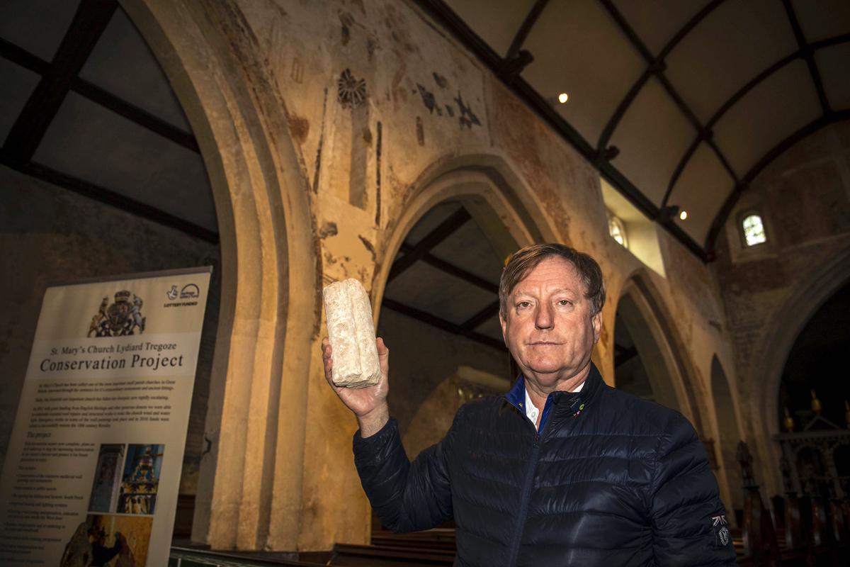 Paul Gardener, Chair of the restoration project at St Mary's Church, holds a piece of debris that was found in the niche alongside the face of a statue of St Christopher, which has remained intact for hundreds of years. Swindon. (©SWNS)