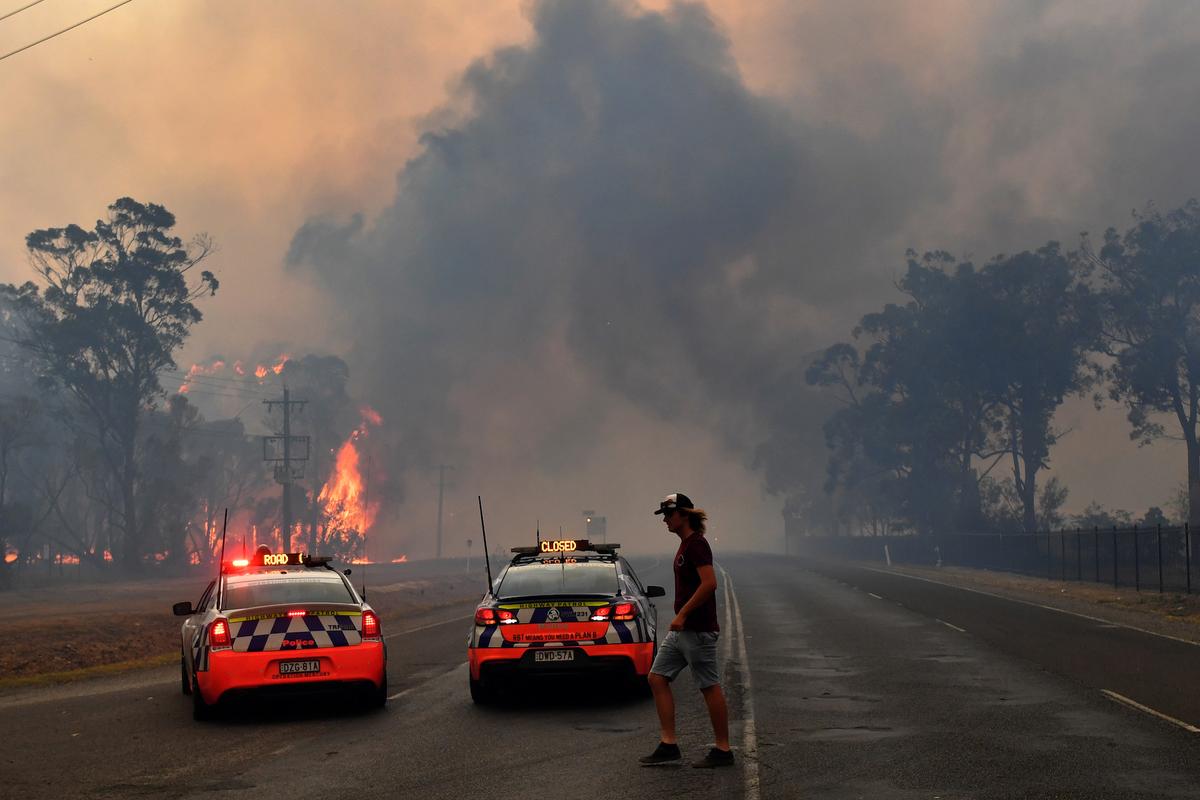 Police block the Old Hume Highway as a blaze jumps the road near the town of Tahmoor as the Green Wattle Creek Fire threatens a number of communities in the south west of Sydney, Australia, Dec. 19, 2019. (AAP Image/Dean Lewins/via Reuters)