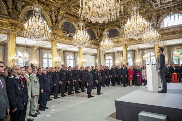 French President Emmanuel Macron stands at attention after addressing Paris Firefighters' brigade and security forces who took part in the fire extinguishing operations of the Notre Dame of Paris Cathedral fire, at the Elysee Palace in Paris, on April 18, 2019. (Christophe Petit Tesson, Pool via AP)
