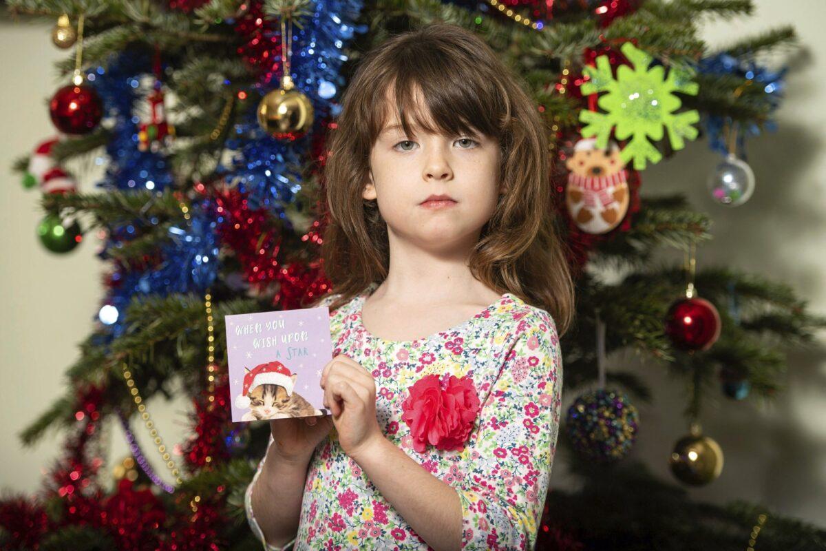 Florence Widdicombe, 6, poses with a Tesco Christmas card from the same pack as a card she found containing a message from a Chinese prisoner, in London, on Dec. 22, 2019. (Dominic Lipinski/PA via AP)