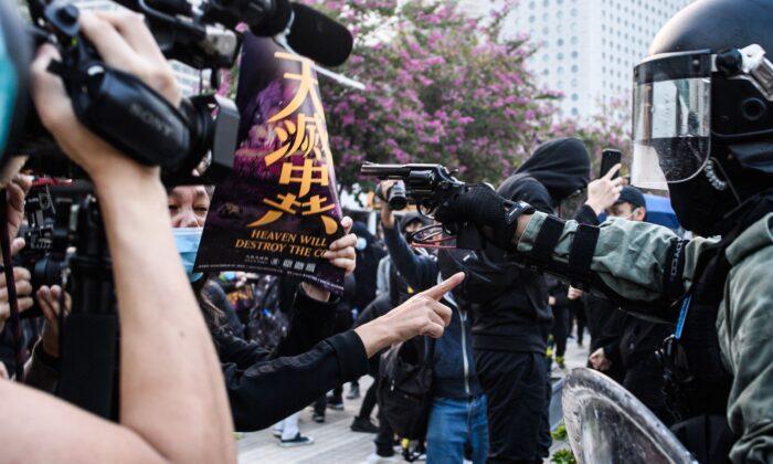 Facing the Barrel of a Gun, Woman Holds Epoch Times Poster to Protest Hong Kong Police