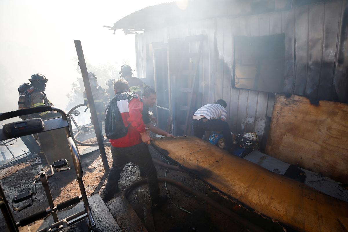 People help firefighters as they work to extinguish a fire in Valparaiso, Chile Dec. 24, 2019. (Reuters/Rodrigo Garrido)