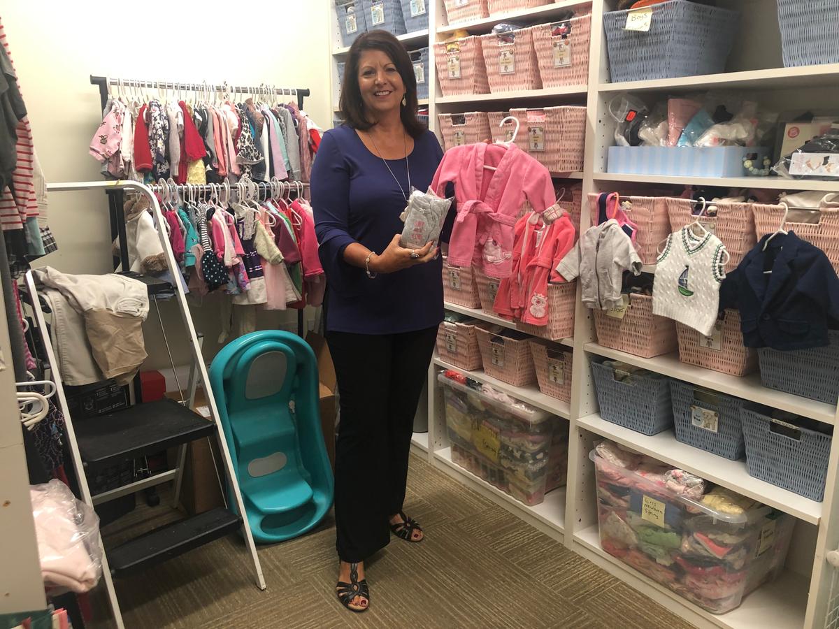 Valerie Hill standing in front of baby supplies at San Jose RealOptions office. (Nathan Su/The Epoch Times)
