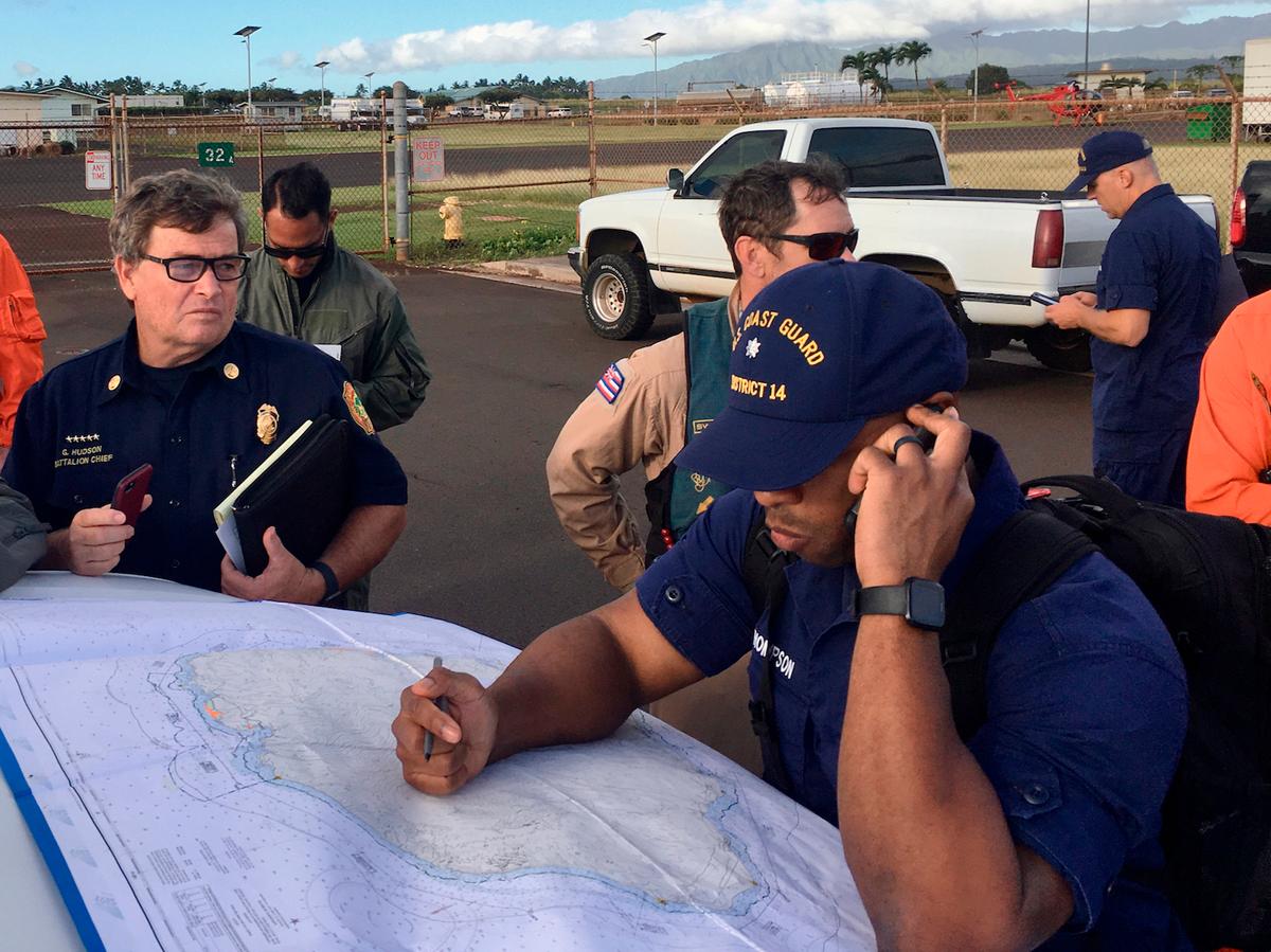 Coast Guard Incident Command Post responders looking over a map of Napali Coast State Wilderness Park for search and rescue for a tour Helicopter that disappeared in Hawaii with 7 people aboard in Kauai, Hawaii on Dec. 27, 2019. (Senior Chief Justin Shackleford/U.S. Coast Guard via AP)