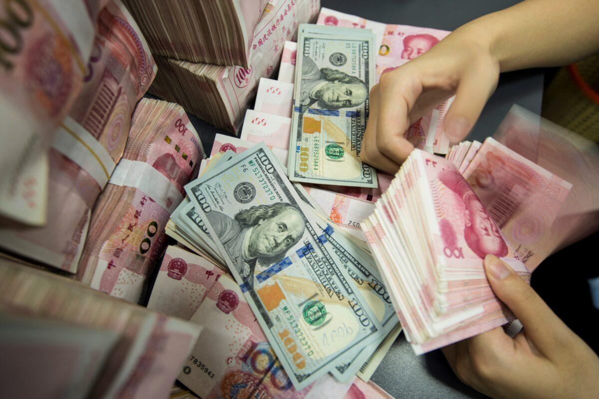  A Chinese bank employee counts 100-yuan notes and U.S. dollar bills at a bank counter in Nantong in China's eastern Jiangsu Province on Aug. 28, 2019. (STR/AFP/Getty Images)