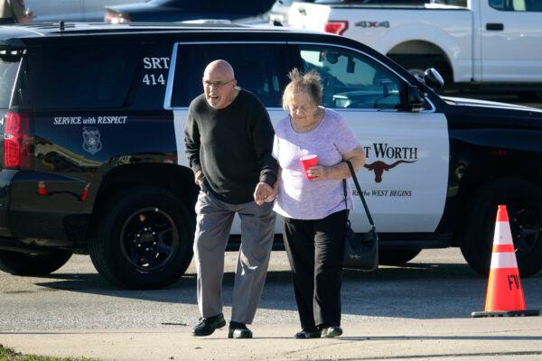 An elderly couple walks from West Freeway Church of Christ hours after a fatal shooting at the church in White Settlement, Texas, on Dec. 29, 2019. (AP Photo/David Kent)