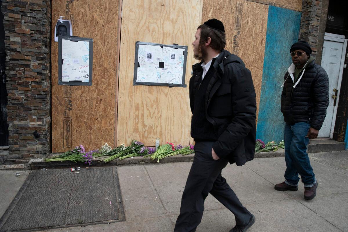 In this Dec. 13, 2019, file photo, men pass a boarded-up kosher grocery store, in Jersey City, N.J., where three people and two gunmen were killed days earlier. New York Mayor Bill de Blasio called the incident a "premeditated anti-Semitic hate crime." (Mark Lennihan/AP Photo)