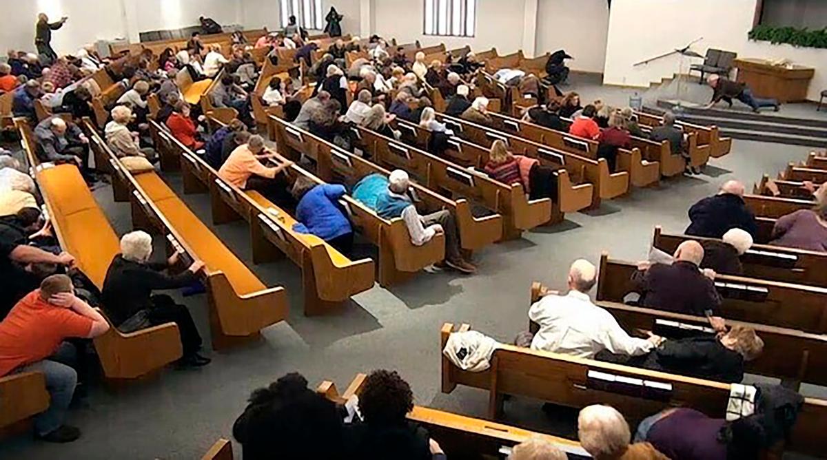 In this still frame from livestreamed video provided by law enforcement, churchgoers take cover while a congregant armed with a handgun, top left, engages a man who opened fire, near top center just right of windows, during a service at West Freeway Church of Christ in White Settlement, Texas, on Dec. 29, 2019. (West Freeway Church of Christ/Courtesy of Law Enforcement via AP)