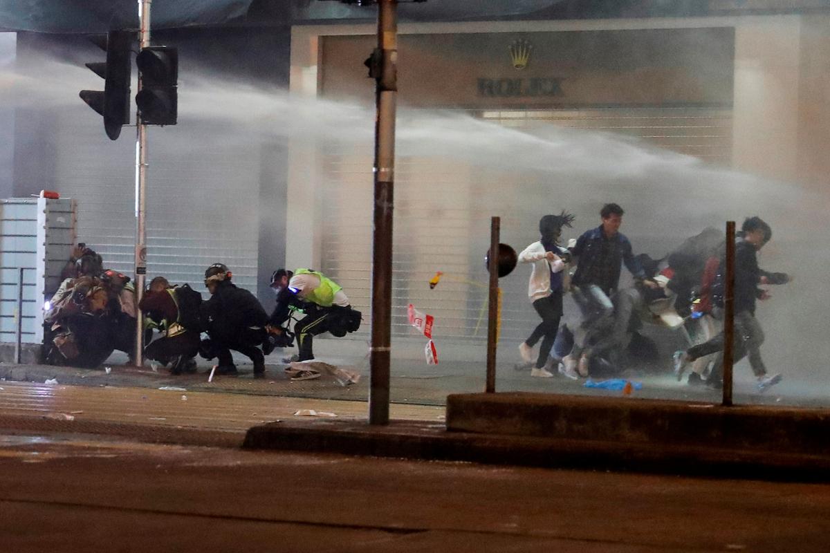 People run away from water cannon fired by riot police during a protest on New Year‘s Eve in Mongkok, Hong Kong on Dec. 31, 2019. (Tyrone Siu/Reuters)