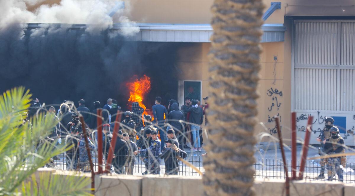 Attackers and assailants set fire to a gate as smoke rises from inside the compound of the U.S. embassy in Baghdad, Iraq, on Jan. 1, 2020. (U.S. Army/Staff Sgt. Desmond Cassell/Task Force-Iraq Public Affairs/Handout via Reuters)