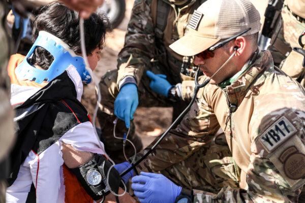 Border Patrol BORSTAR agent Eric Carrillo takes an injured man's blood pressure in the Imperial Sand Dunes, Calif., on Nov. 30, 2019. (Charlotte Cuthbertson/The Epoch Times)
