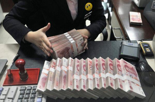 A clerk arranges bundles of 100 Chinese yuan banknotes at a branch of China Merchants Bank in Hefei, Anhui Province on March 17, 2014. (Reuters)
