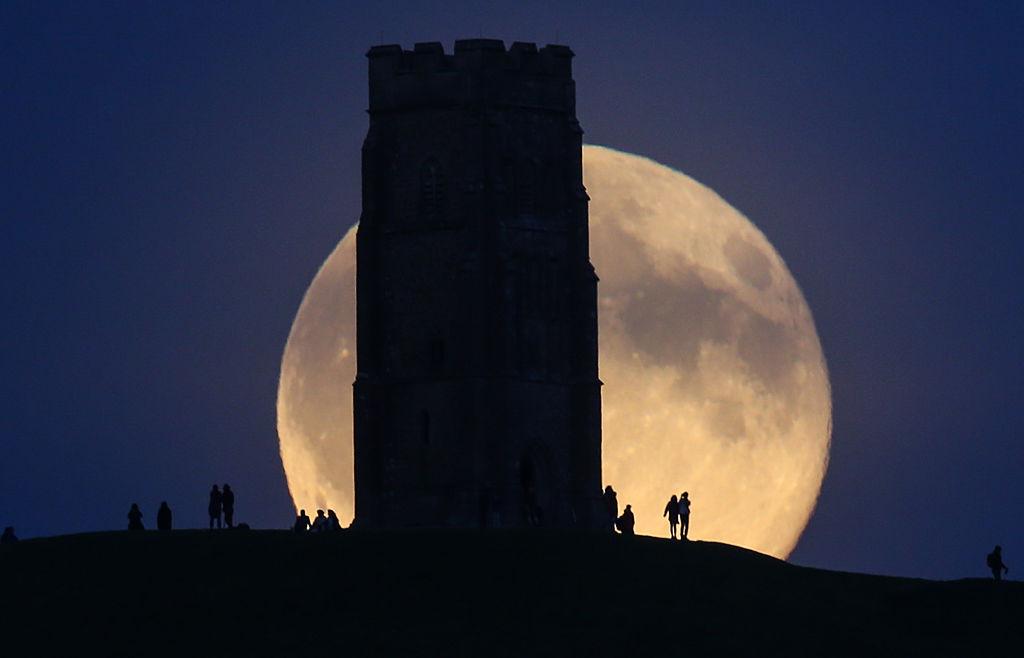 The full "blue" moon rises over crowds gathered on Glastonbury Tor in Somerset, England, on July 31, 2015. (©Getty Images | <a href="https://www.gettyimages.com/detail/news-photo/the-moon-rises-over-people-gathered-on-glastonbury-tor-on-news-photo/482616672?adppopup=true">Matt Cardy</a>)
