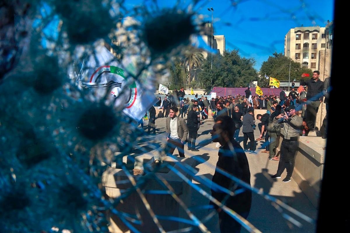 Protesters are seen through a broken window of a checkpoint belonging to the U.S. embassy, in front of the U.S. embassy in Baghdad, Iraq, on Dec. 31, 2019. (Khalid Mohammed/AP Photo)