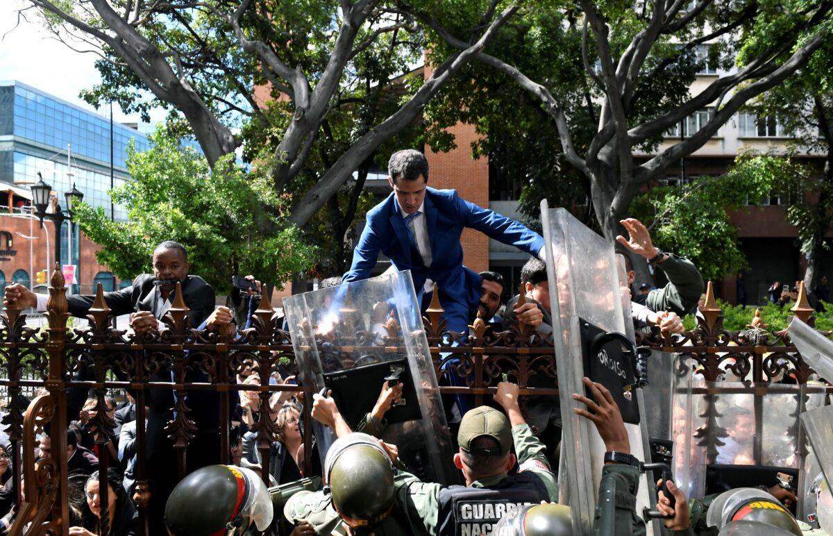 Venezuelan opposition leader Juan Guaido, who many nations have recognized as the country's rightful interim ruler, is helped to climb a railing in an attempt to reach the National Assembly building in Caracas, on Jan. 5, 2020. (Federico Parra/AFP via Getty Images)