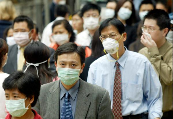 People wear masks on the street to protect against a deadly pneumonia virus in Hong Kong, on March 31, 2003. (Peter Parks/AFP/GettyImages)