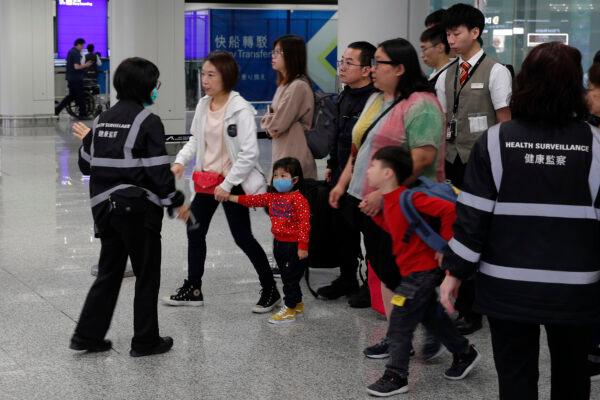 Health surveillance officer use device to check temperature of passengers before the immigration counters at International airport in Hong Kong, on Jan. 4, 2020. (AP Photo/Andy Wong)