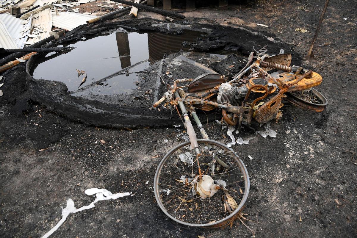 A motorbike lies next to a melted water tank at a burnt out property in Kiah, Australia, on Jan. 8, 2020. (Reuters/Tracey Nearmy)