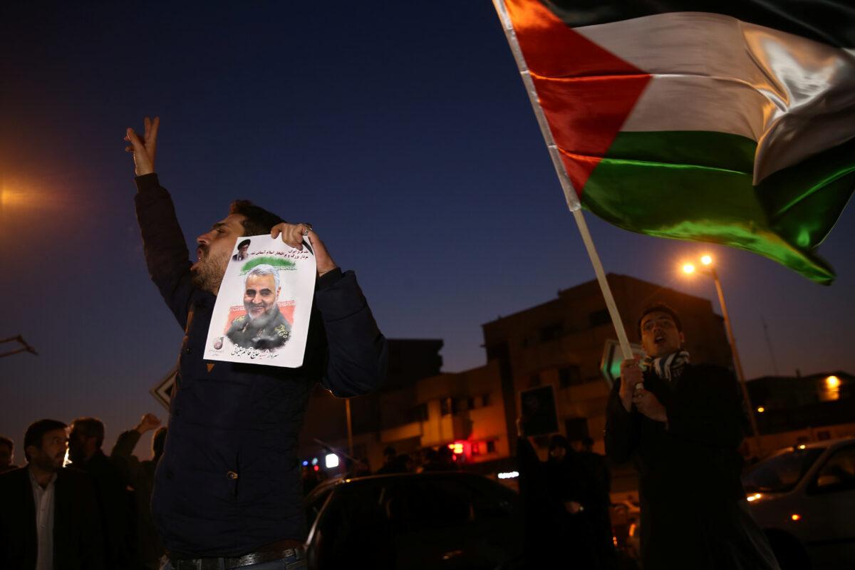 A man holds a picture of late Iranian General Qassem Soleimani, as people celebrate in the street after Iran launched missiles at U.S.-led forces in Iraq, in Tehran, Iran, on Jan. 8, 2020. (Nazanin Tabatabaee/WANA (West Asia News Agency) via Reuters)