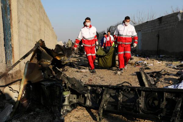 Rescue workers carry the body of a victim of a Ukrainian plane crash among debris of the plane in Shahedshahr, southwest of the capital Tehran, Iran, on Jan. 8, 2020. (Ebrahim Noroozi/AP Photo)