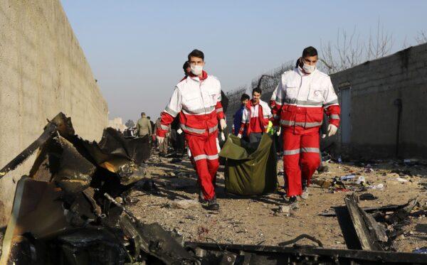 Rescue workers carry the body of a victim of a Ukrainian plane crash among debris of the plane in Shahedshahr, southwest of Tehran, Iran, on Jan. 8, 2020. (Ebrahim Noroozi/AP Photo)