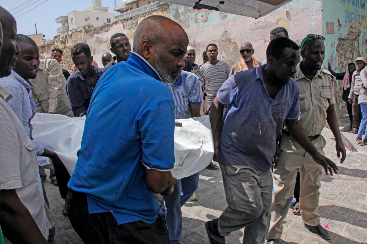 People remove a dead body after a vehicle bomb attack on a security checkpoint located near the presidential palace, in Mogadishu, Somalia, on Wednesday, Jan. 8, 2020. (Farah Abdi Warsameh/AP)
