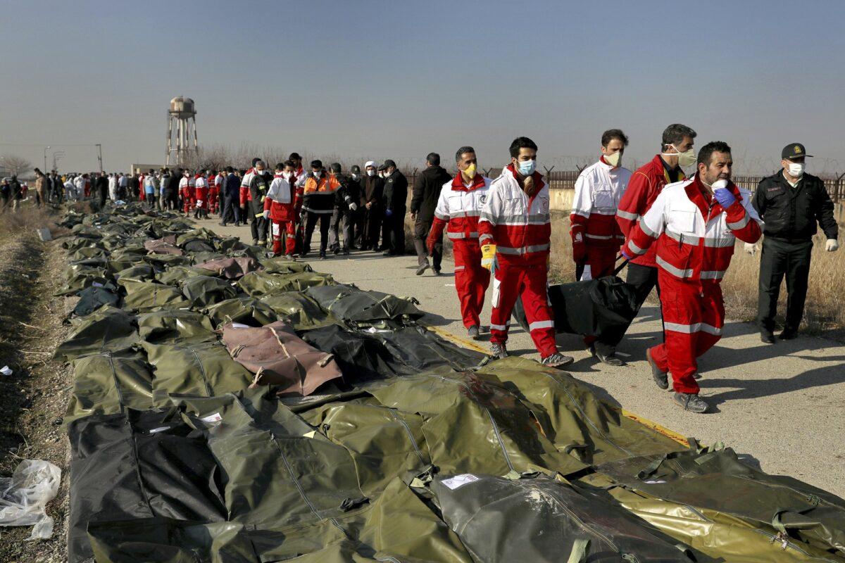 Rescue workers carry the body of a victim of a Ukrainian plane crash in Shahedshahr, southwest of the capital Tehran, Iran on Jan. 8, 2020. (Ebrahim Noroozi/AP Photo)