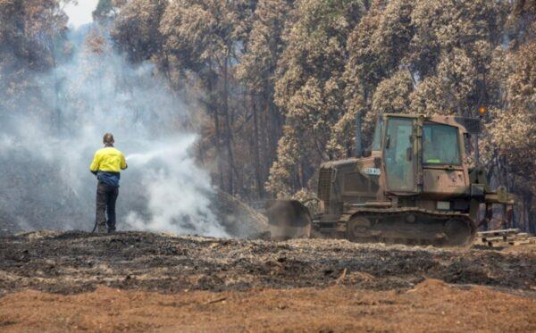 An Australian Army combat engineer utilizes a JD-450 Bulldozer to spread out burnt woodchip at the Eden Woodchip Mill in southern New South Wales, Australia, on Jan.11, 2020. (Bill Solomou/Reuters)