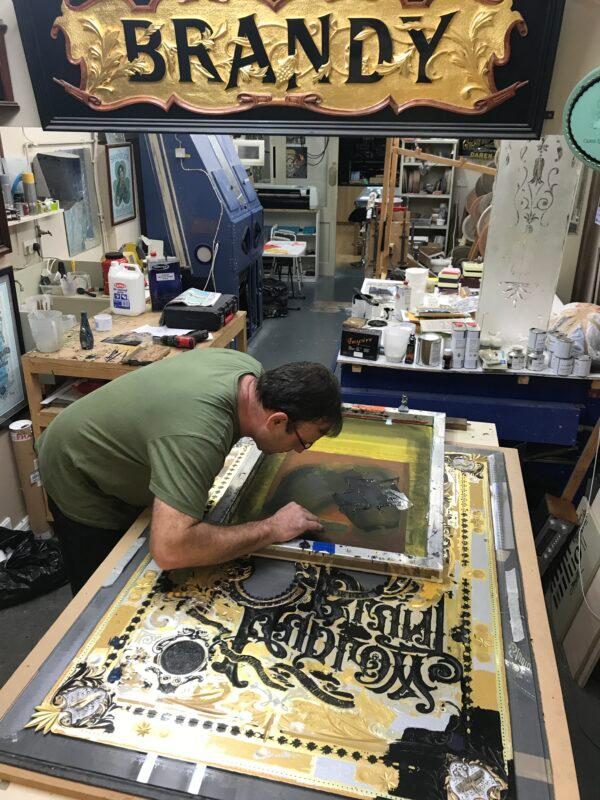 Reverse glass painter David Adrian Smith works on a sign in his workshop. (Courtesy of David A. Smith)
