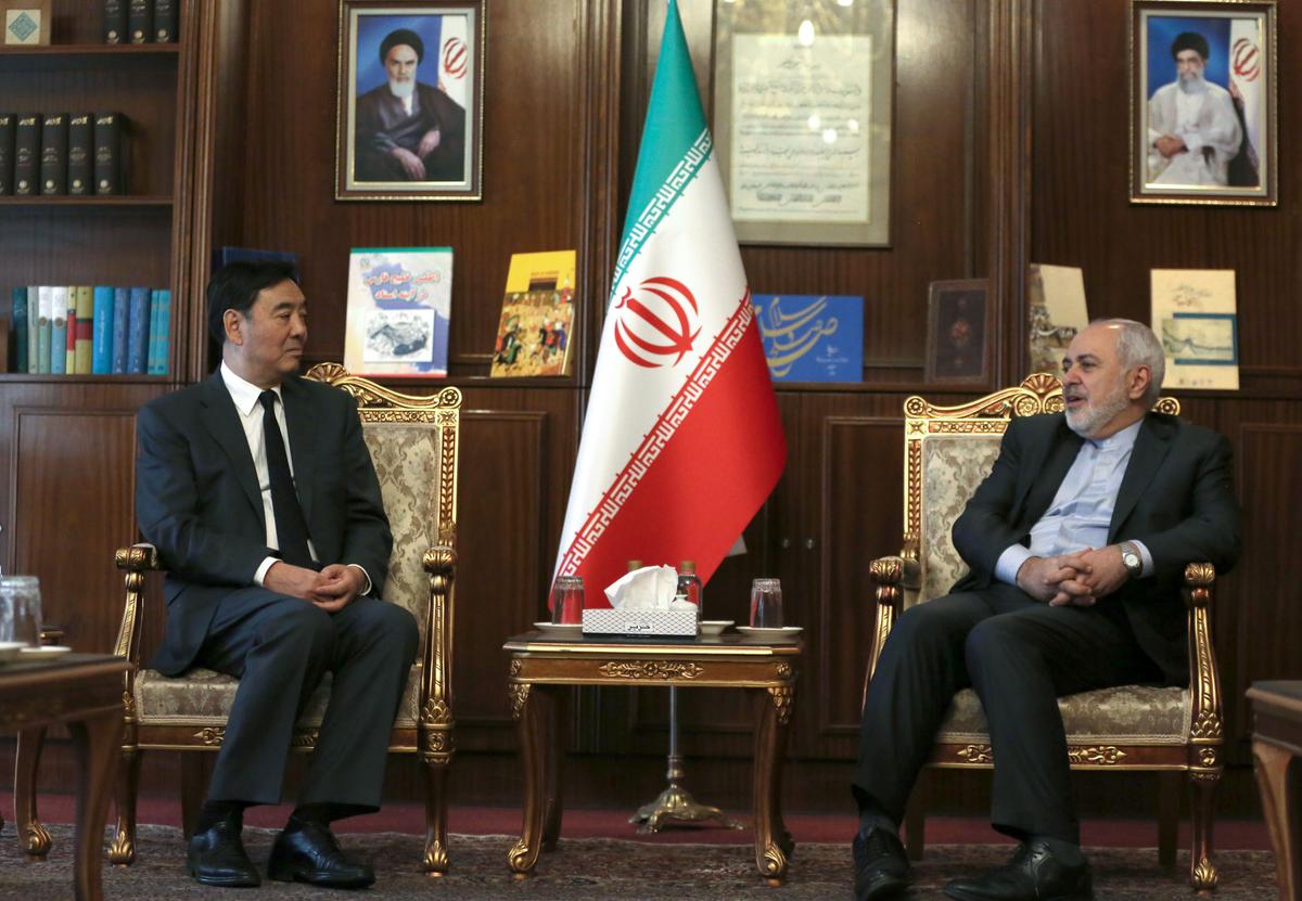 Iran's Foreign Minister Mohammad Javad Zarif (R) meets with China's special envoy for Middle East affairs Zhai Jun in Tehran on Oct. 22, 2019. Behind them hang portraits of Iran's Supreme Leader Ayatollah Ali Khamenei (R) and late founder of the Islamic Republic, Ayatollah Ruhollah Khomeini. (ATTA KENARE/AFP via Getty Images)