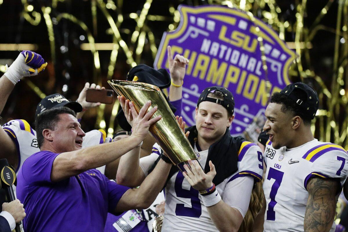 (L) LSU head coach Ed Orgeron and (C) quarterback Joe Burrow hold the trophy beside safety Grant Delpit after an NCAA College Football Playoff national championship game against Clemson in New Orleans on Jan. 13, 2020. (Sue Ogrocki/AP Photo)